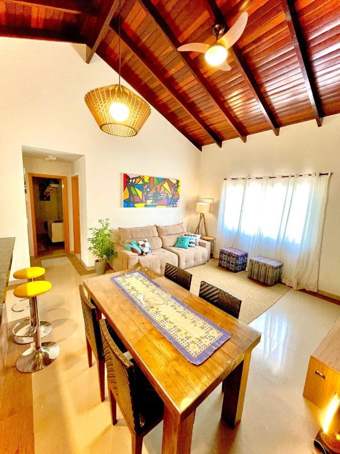 Sala de estar do Linda casa em Juquehy a 150 metros da praia com mesa de jantar com quatro cadeiras a frente ao fundo o sofá com dois puffs.