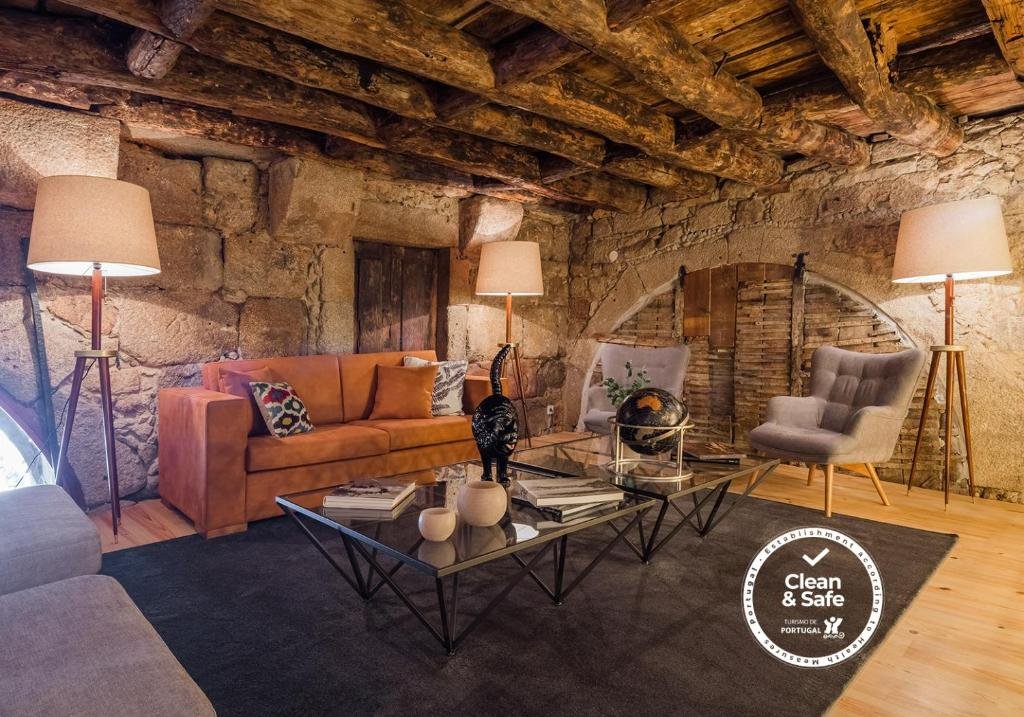 Sala de estar do Porto River com mesa de vidro a frente da imagem, atrás da mesa um sofá grande com dois abajures ao lado do lado direito do sofá duas poltronas.