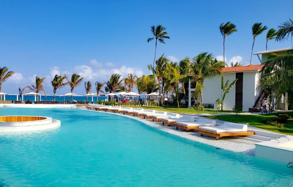 Piscina do The Westin Porto de Galinhas All-Inclusive com muitas espreguiçadeiras ao redor e um pequeno gramado com palmeiras, além da vista para o mar