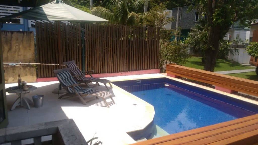 Uma piscina em Casa em Toque-Toque Pequeno, ao redor algumas árvores, duas espreguiçadeiras e um pequeno deck