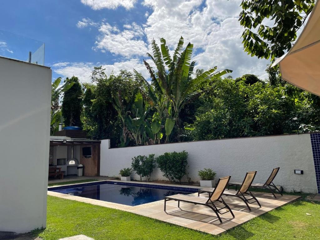 Vista da área de lazer com piscina e cadeiras em volta na Casa em Condomínio Maresias em Toque-Toque Pequeno.