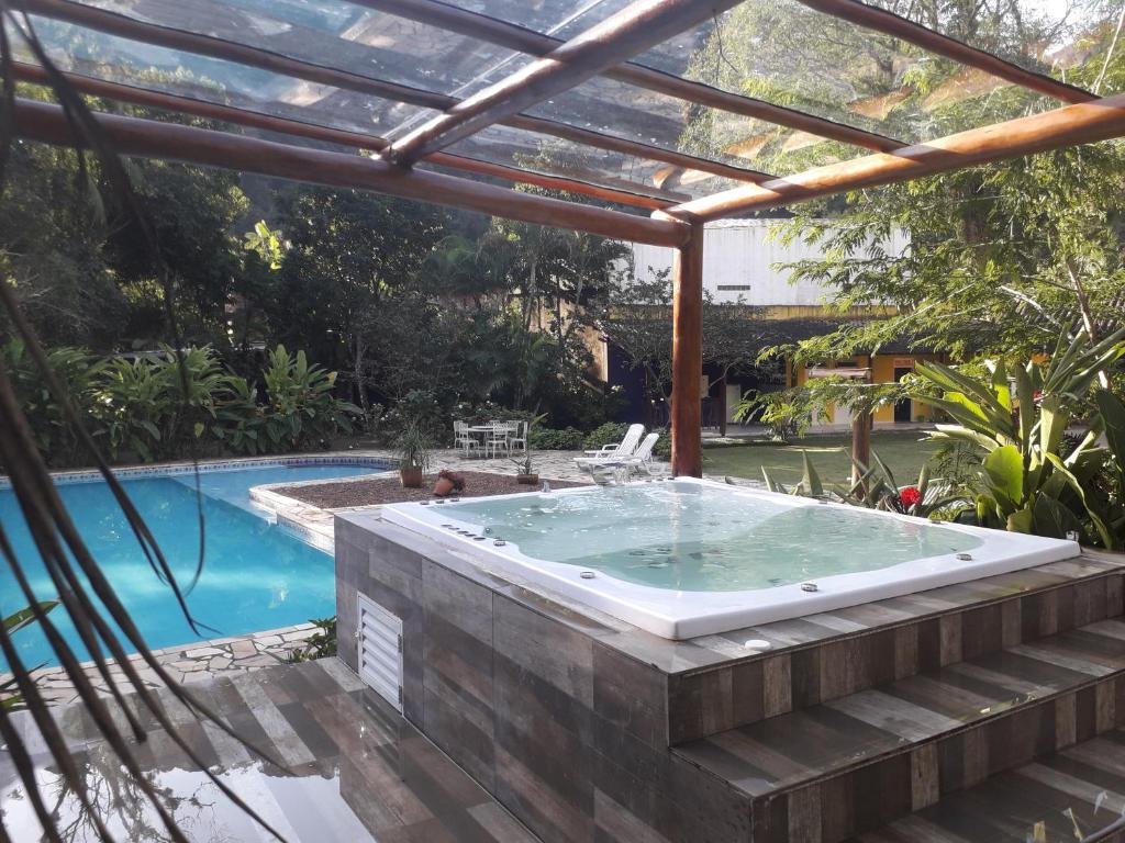 Vista da área de lazer com piscina e banheira na Jacuzzi Aquecida - Lareira - Inverno em Linda Casa Litoral Norte em Juquehy.